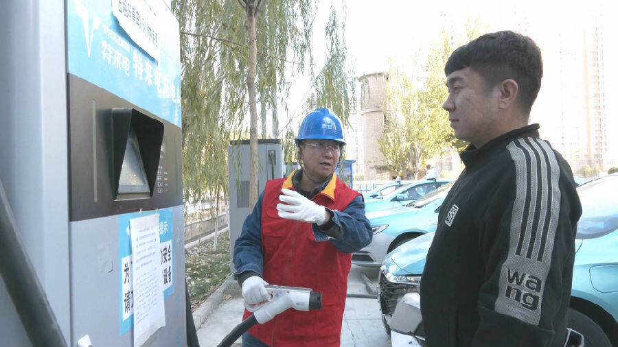 圖為國家電網工作人員為出租車駕駛員進行充電輔導（王新宏 攝）